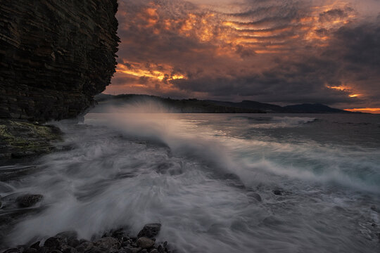 Sunset on the Lastron nudist beach in Zierbena, Bizkaia, with the water between the rocks on the shore