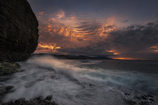 Sunset on the Lastron nudist beach in Zierbena, Bizkaia, with the water between the rocks on the shore