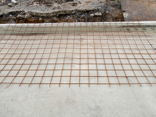 The metal wire mesh on the concrete floor.