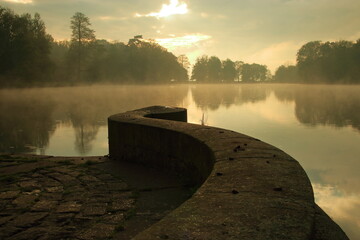 Staw w parku o wschodzie słońca z unoszącymi się mgłami © Lucky