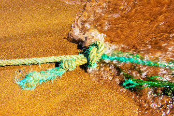 Closeup of an old nautical rope for mooring fishing boats on the Atlantic Ocean in Gran Canaria during an incoming water wave. Rope and knot background texture.