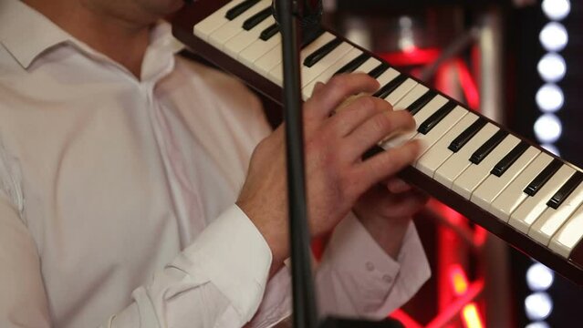 The musician plays a keyboard wind instrument. Playing the piano. Melodica musical wind instrument.