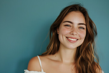 A woman with long hair and freckles smiles for the camera