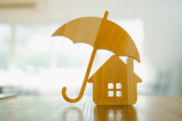 Model of umbrella with house on wooden table concept of the system of insurance savings and Housing insurance against impending loss and fire, building fire insurance concepts.