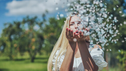 A girl blows a multi-coloured paper confetti out of her hands.