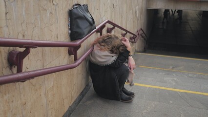 A young girl crying by the stairs in the subway.