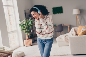 Photo of cheerful dreamy lady dressed striped pullover enjoying music headphones indoors apartment...