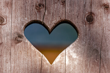 Close-up of heart hole in wooden door of outdoor toilet at Swiss City of Wallisellen on a sunny spring day. Photo taken April 18th, 2024, Wallisellen, Canton Zürich, Switzerland. - Powered by Adobe