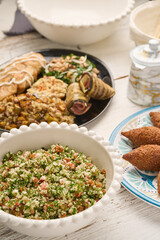 Fresh vegan Tabbouleh salad made of tomato, parsley, onion and couscous in bowl (Selective Focus, Focus one third into the salad) Other dishes arround