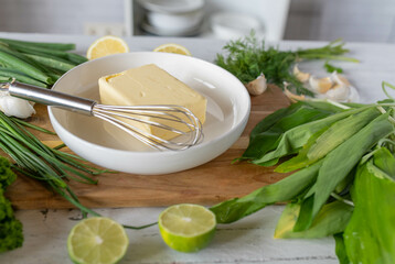 Ingredients for making herb butter on a cutting board. With ramson, parsley, garlic cloves, dill,...