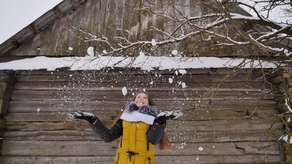 A young girl tossing snow in the winter in the countryside.