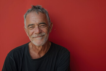 Obraz premium A man with gray hair and a beard is smiling in front of a red wall