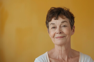 An older woman smiles for the camera with a yellow background