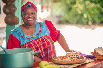 Portrait of an adult woman standing in her kitchen looking at a camera. Proud African American...