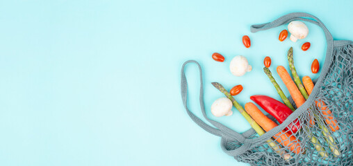 Mesh bag with vegetables, shopping grocery, healthy food ingredients, asparagus sprout, mushrooms, carrots and tomatoes, zero waste 