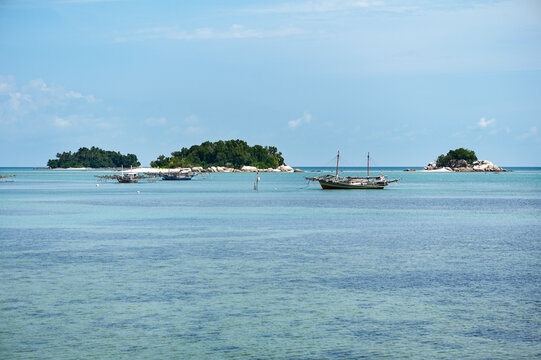 Tanjung Binga fishing village beach with fishing boats in front of Kera Kecil Island and other islands Belitung, Bangka Belitung, Indonesia