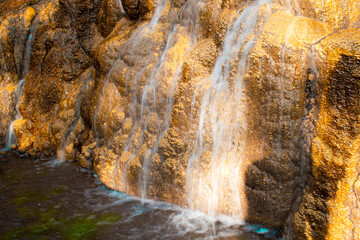 Imagen de una cascada o caída de agua sobre unas rocas al atardecer en horizontal 