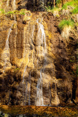 Imagen vertical de una montaña rocosa con caída de agua tipo cascada