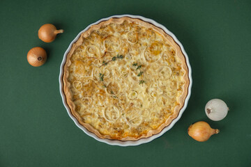 Flat lay of homemade onion cake on the green background. Traditional quiche pie with steamed...