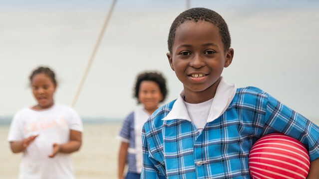 Portrait of a Gar&iacute;funa boy on the beach, holding a red plastic ball.