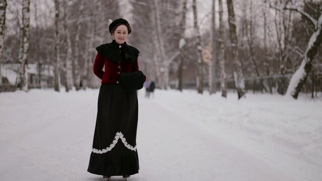 In a snow-covered park, surrounded by snow trees, a lady in an antique outfit and a fur coat is skating, recalling the elegance of old times.