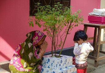 Grandmother teaching her granddaughter to respect holy basil as a part of hindu culture 