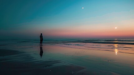 Lone person viewing the moon rise on the beach