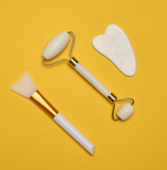 White jade gouache massager and massage jade roller on a yellow background