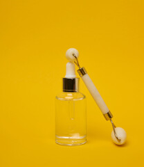 White transparent glass bottle with pipette and roller massager