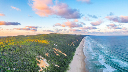 Aerial drone view of Teewah Beach in Cooloola National Park north of Noosa Heads, on the Sunshine Coast in the state of Queensland, Australia. Shot during sunset giving a dreamy feeling to the photo.