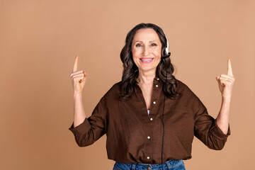 Photo portrait of attractive senior woman hot line point up empty space dressed stylish brown...