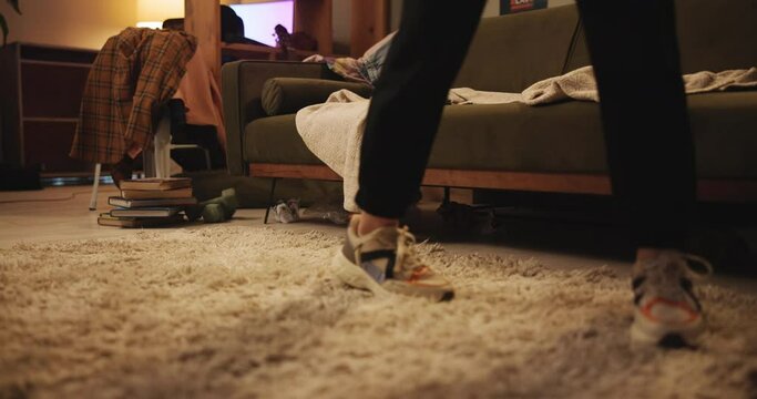 Stress, walking and feet of person in home with anxiety, messy floor and sofa in dorm. Worry, mental health and student with depression pacing on carpet with sneakers, insomnia or nervous at night