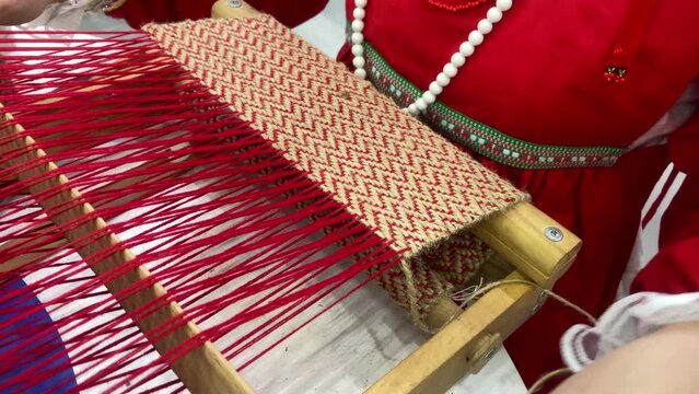 Woman weaving traditional Asian carpet . Handmade carpet embroidery . Women 's hands create a pattern using multi-colored threads . Close up view . Weaving machine . Needlework . Carpet-makers