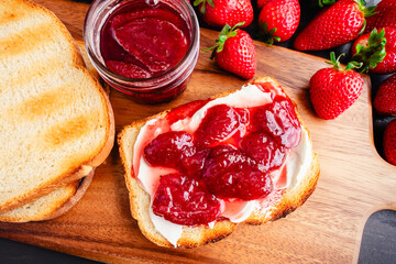 Slice of Toast Covered in Homemade Strawberry Preserves and Cream Cheese: Sliced toasted white bread and homemade strawberry preserves and Neufchatel