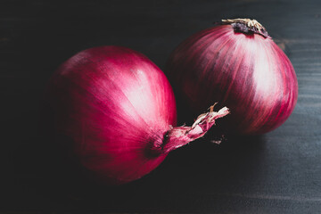 Pair of Whole Red Onions on a Dark Wood Background: Vintage-style photo of a group of two purple Spanish onions on a dark wooden table