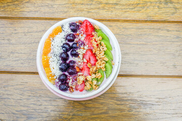 Healthy and colorful Breakfast Acai smoothie bowl with blueberries,kiwi fruit,chia seeds and coconut flakes on wooden background,close-up, top view, space for text.