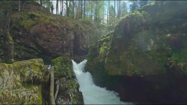 fpv drone flying between rocks over ognon river and waterfalls in cascade de servance Vosges region