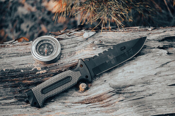 Hunting knife and compass on a wooden background. Concept of outdoor recreation.