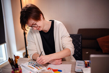 Artist with brush in hand applies vibrant watercolors to paper, a study in concentration and the beauty of the creative process