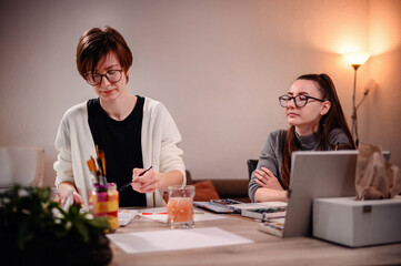 In a creative session, one artist paints while the other plans, a perfect example of collaborative effort and artistic consultation.