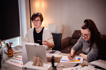 Two artists intently craft a color narrative, one with brush in hand, the other with pen poised,...