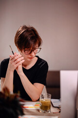 An artist pauses for reflection, brush in hand, as she contemplates her next stroke on a color...