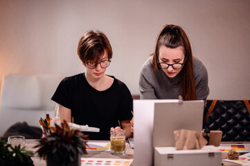 Artists share a moment of collaboration, one meticulously mixing paint while the other evaluates...