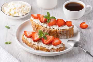 Homemade Crispbread toast with Cottage Cheese and Strawberry on white wooden board