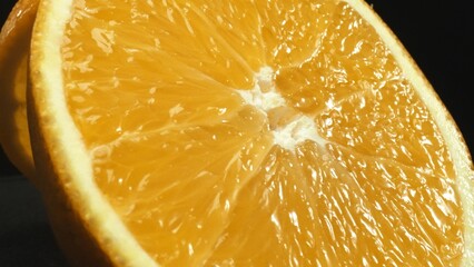 A macrography capture of an orange slice, placed against a sleek, isolated black backdrop, unfolds as a visual masterpiece of citrus allure. A slice of orange with black background. Comestible.
