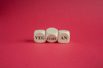 Turned a cube and changes the word vegetarian to vegan. Beautiful red background. Symbol to change from a vegetarian to a vegan person.
