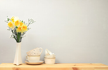 Kitchen table with coffee cups and spring flowers. Simple home kitchen interior, mockup for product...