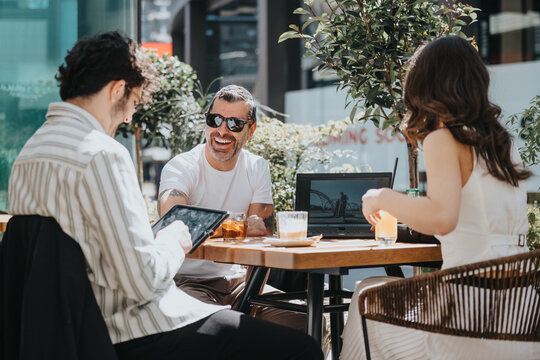 Entrepreneurs of different generations discuss strategies and analyze reports at a modern coffee bar, using digital devices to plan business growth.