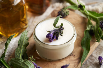 A jar of homemade comfrey root ointment with fresh plant