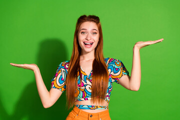 Photo portrait of attractive young woman hold shocked compare empty space dressed stylish retro clothes isolated on green color background